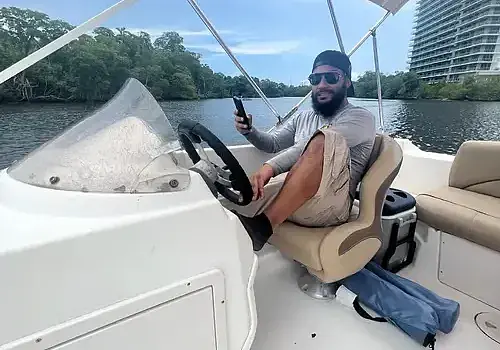  Alexander is seated in a boat supported by Marine Kings of Miami boat maintenance services.